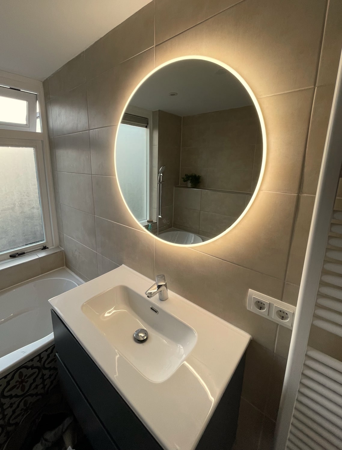 Ronde badkamer spiegel met verlichting op grote horizontale tegels