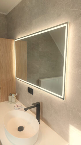 Miroir salle de bain moderne avec éclairage périphérique sur un mur de carrelage gris