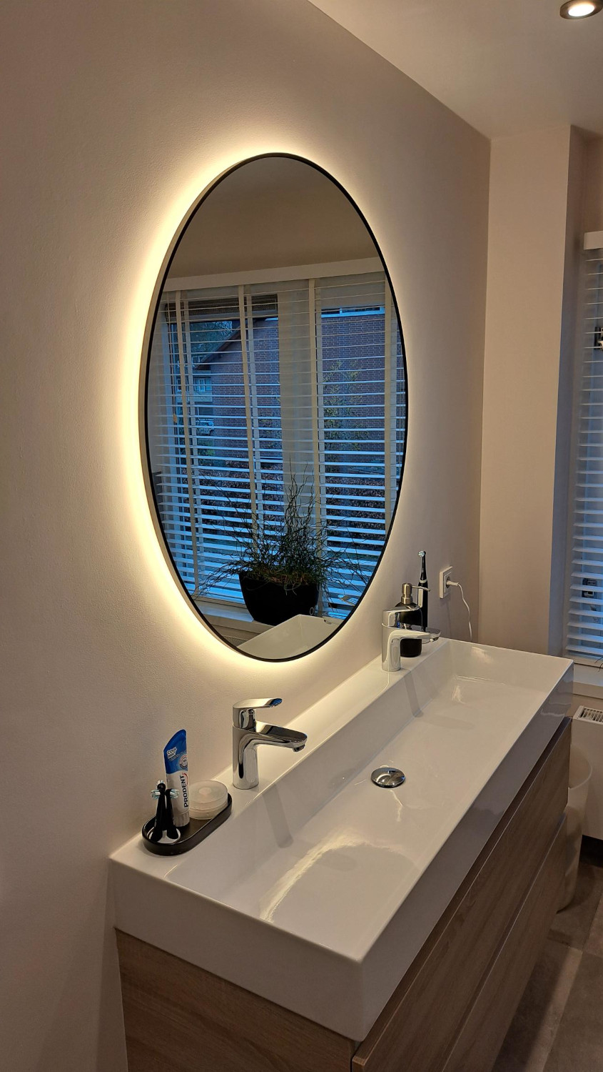 Zwarte ronde badkamerspiegel op gestuukte wand