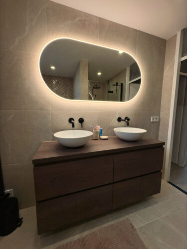 Grote ovale badkamer spiegel op taupe tegel