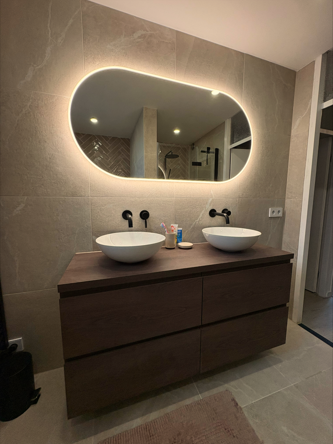 Grote ovale badkamer spiegel op taupe tegel