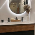 Zwarte ronde badkamer spiegel met led verlichting op witte tegel