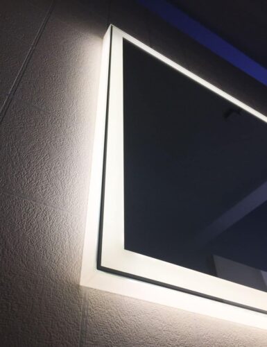 De spiegel is rondom afgewerkt met lichtdoorlatende profielen, zodat de verlichtings armaturen vanaf de zijkant niet zichtbaar zijn