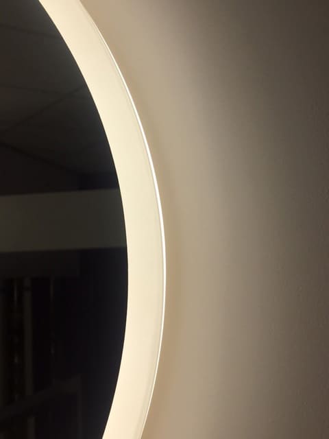 De stijlvolle lichtbaan is tegen de spiegelrand geplaatst en zorgt voor praktische verlichting in het gezicht. De indirecte verlichting schijnt sfeervol over de wand.