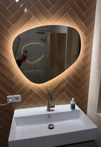 Miroir salle de bain organique sur mur de carrelage à chevrons