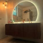 Organische spiegel boven een badkamermeubel met afgeronde hoeken