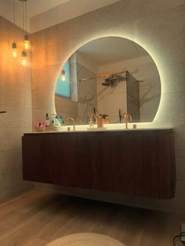 Organische spiegel boven een badkamermeubel met afgeronde hoeken