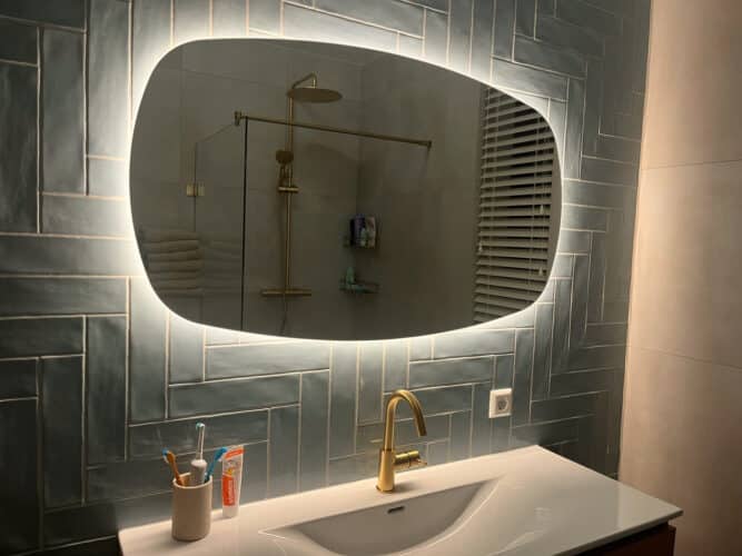 Deens ovale spiegel op een visgraat tegel wand