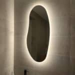 Spiegel met vrije vorm op zandkleurige tegel