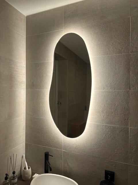 Spiegel met vrije vorm op zandkleurige tegel