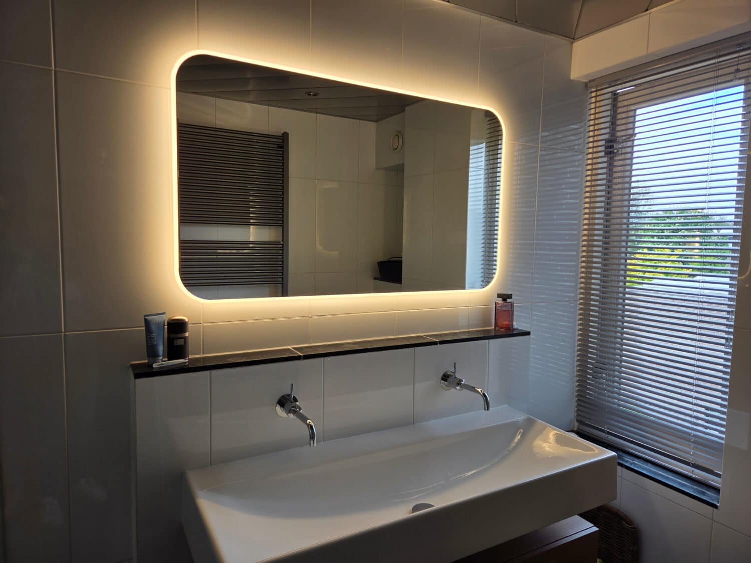 Miroir aux coins arrondis sur un mur de carrelage blanc