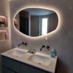 Miroir salle de bain organique sur grand carrelage en marbre