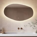Deze trendy badkamer spiegel met organische vorm is van alle gemakken voorzien, zoals: ambi verlichting, spiegelverwarming, dimfunctie en een instelbare lichtkleur