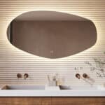 Deze trendy badkamer spiegel met organische vorm is van alle gemakken voorzien, zoals: ambi verlichting, spiegelverwarming, dimfunctie en een instelbare lichtkleur